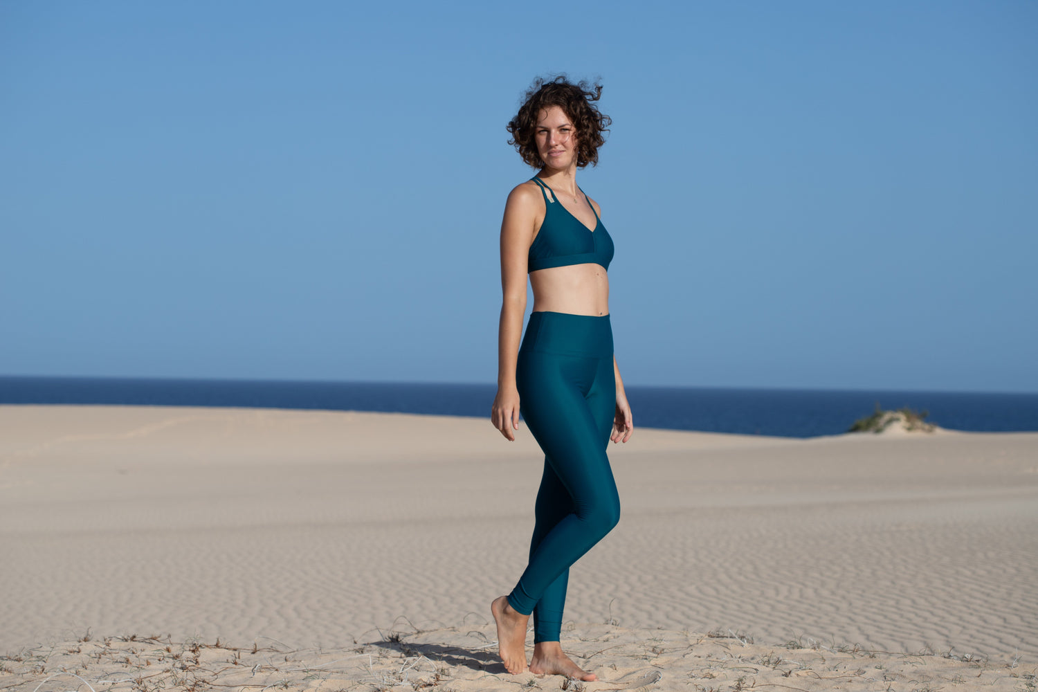 Frau am Strand in nachhaltig produzierter Inaska Leggings und Inaska Bikini Top