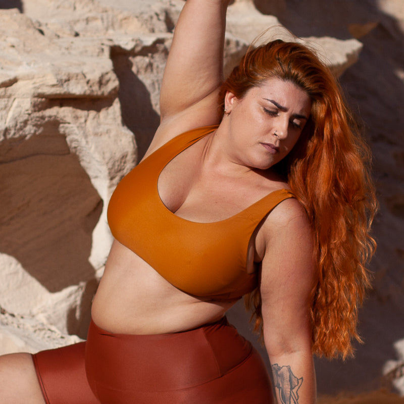 Frau mit ausgestrecktem Arm trägt Bikinitop in Ocker