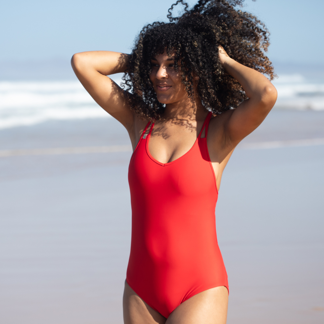 Dame mit Meer im Hintergrund trägt Badeanzug in Rot